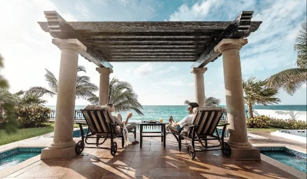 Couple sits on patio at Grand Residences Cancun Resort and overlook the Caribbean Sea.