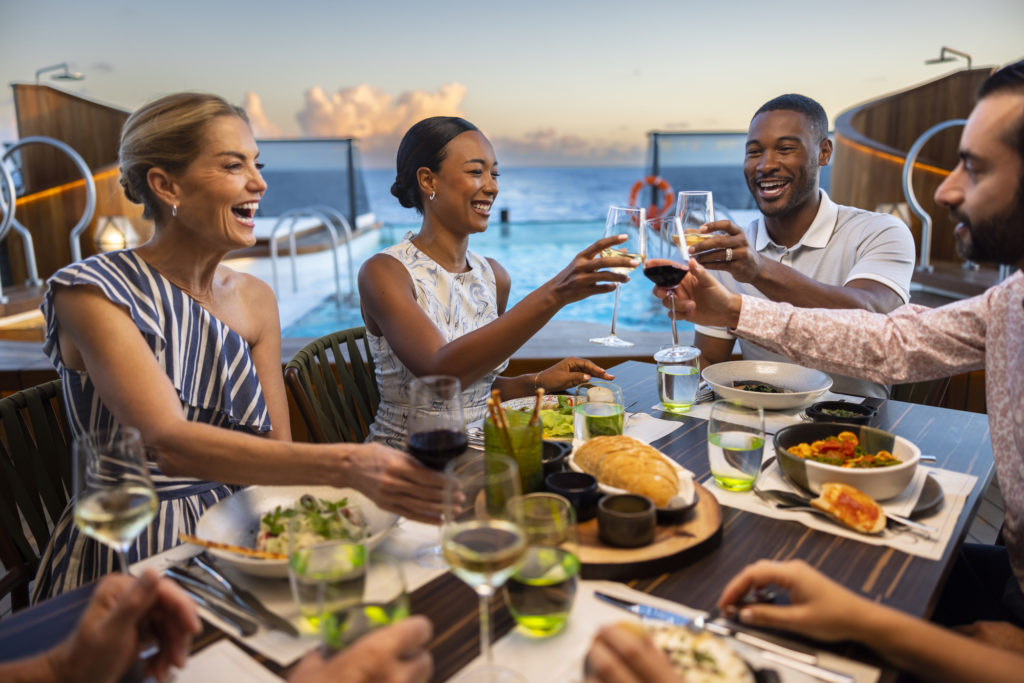Two couples toasting each other over dinner on a deck of the Seabourn Venture cruise ship.
