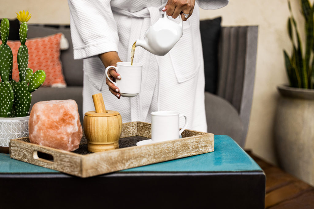 Woman in bathrobe pouring tea into cup at Miramonte Resort health spa.