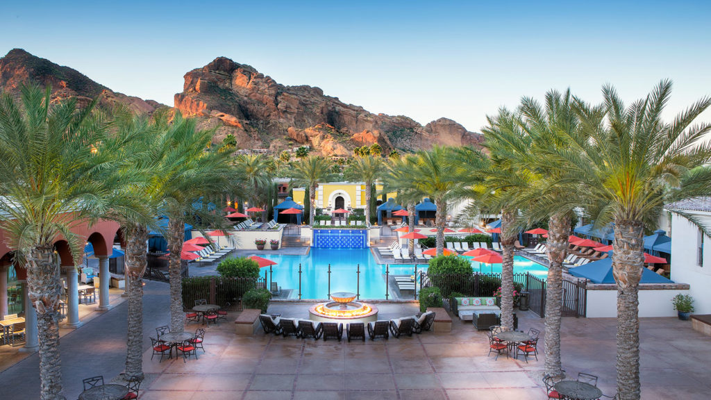 Beautiful outdoor pool surrounded by colorful deck chairs, fountains and Moorish architectural decoration at an Omni Hotel.