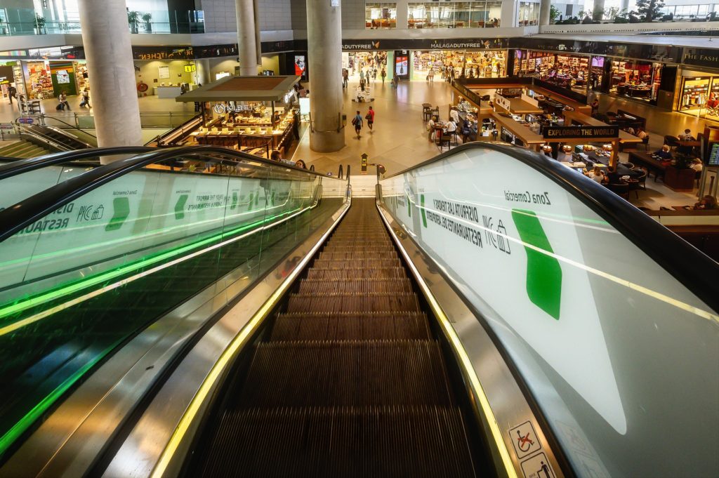 View of escalator in new terminal going down to a level full of shops at Spain's Malaga Airport.