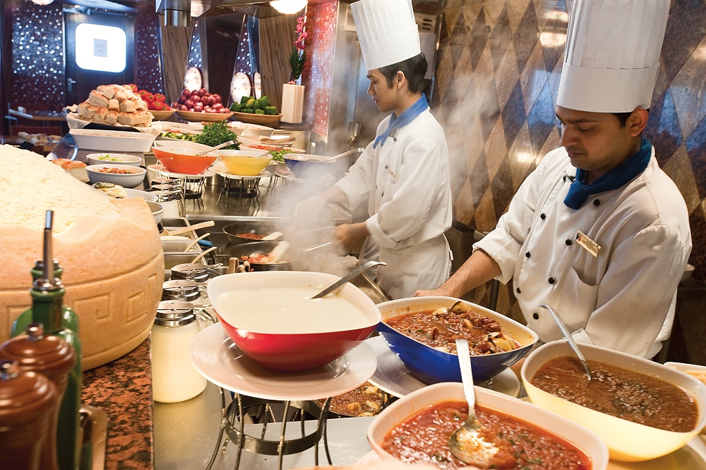 Chefs preparing several dishes in Carnival Cruise ship kitchen.
