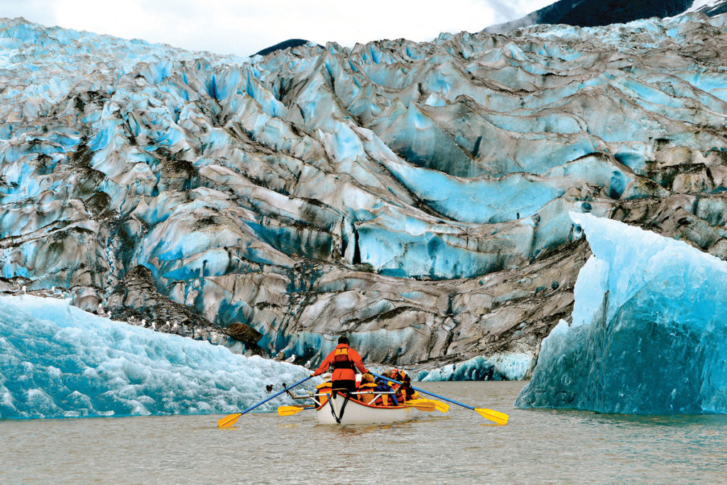 Native American canoe rowed by naturalist guide leads Cunard cruise passengers to glacier viewing in Alaska.