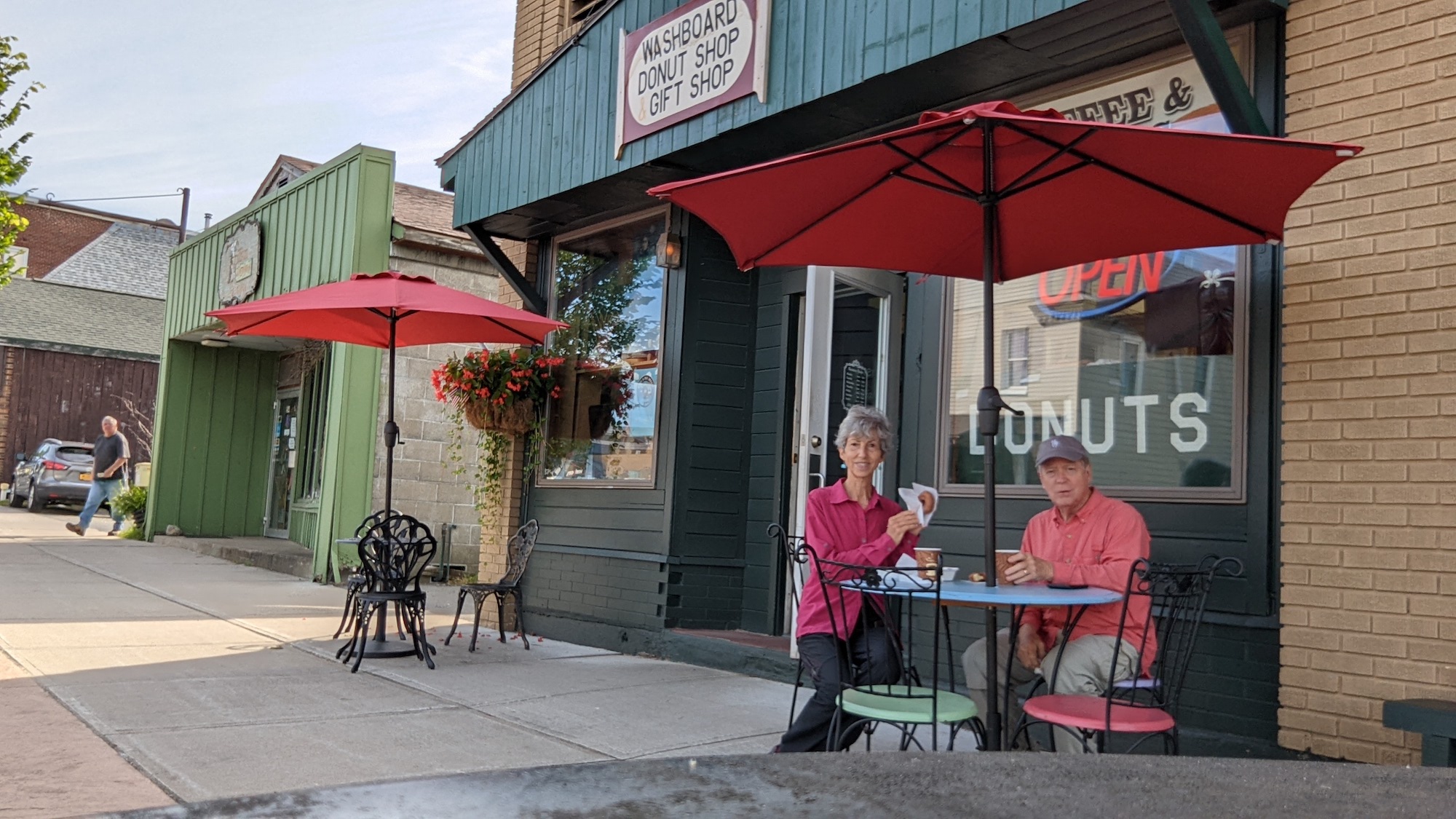 Couple sits outside a donut shop on a small town main street.