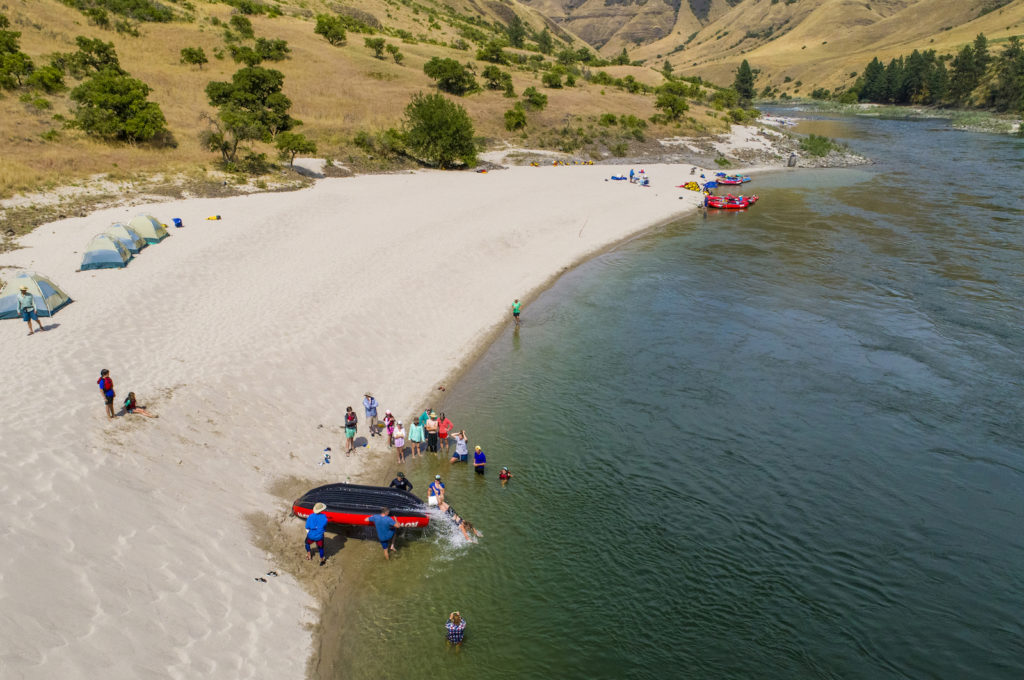 A group of rowers with a whitewater raft puts in at a beach along the Lower Salmon River in Idaho with ROW Adventures.