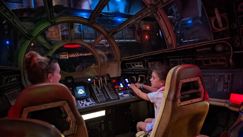Girl and mom pilot the Millennium Falcon at Walt Disney World's Star Wars land ride, Smuggler's Run.