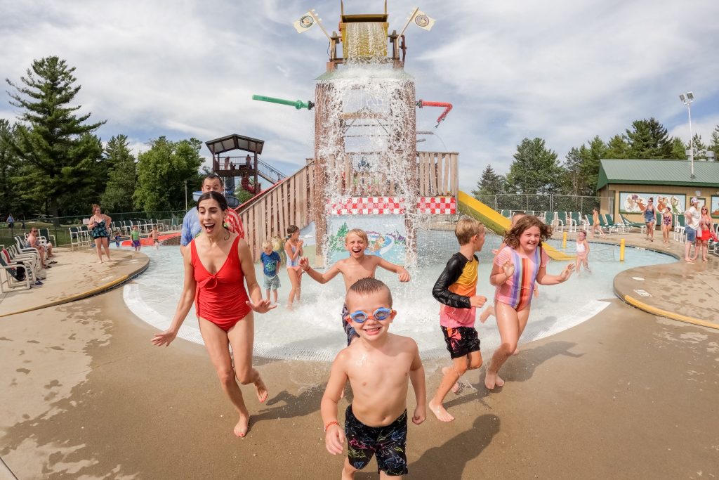 Kids play in a splash pad with a dump bucket at the Caledonia, Wisconsin Jellystone Park Camp-Resort.