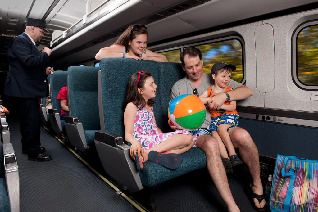 Família com equipamento de praia a bordo do trem Downeaster da Amtrak indo para o Maine nas férias de verão.