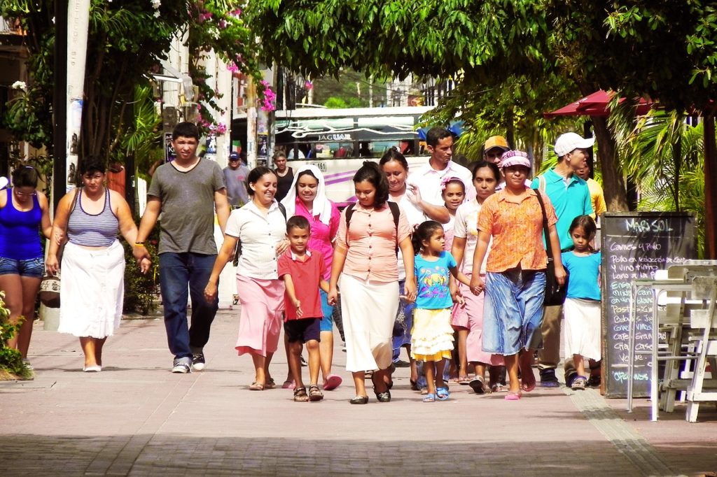 Large group of Latino family members walk down street in Spanish speaking town.