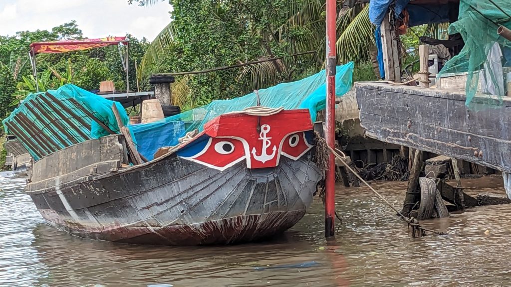 A Vietnamese rice barge with the traditional talisman of guiding eyes painted on its bow unloads a shipment of rice.