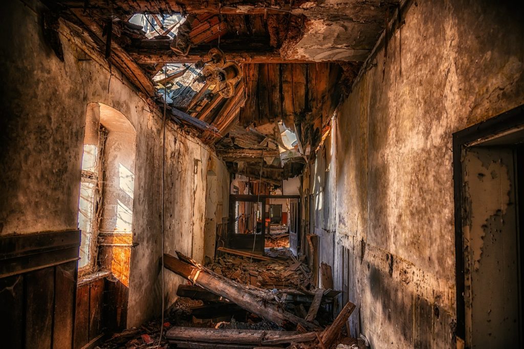 The hallway of a house in ruins looks very spooky.