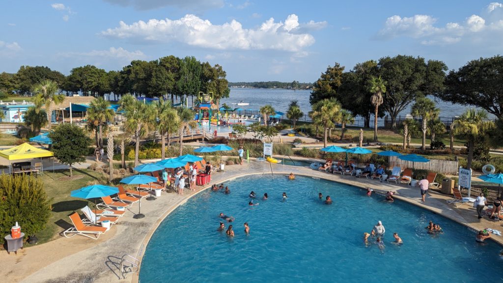 Family pool and deck with Lake Conroe in the background, as seen from top of waterslide at Margaritaville Lake Resort Lake Conroe.