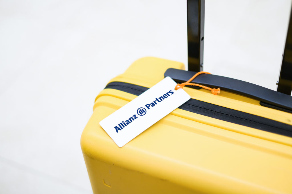 Yellow suitcase with Allianz Partners luggage tag.