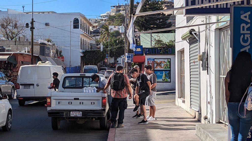 Busy sidewalks and vehicle traffic crowd the downtown Cabo San Lucas area.