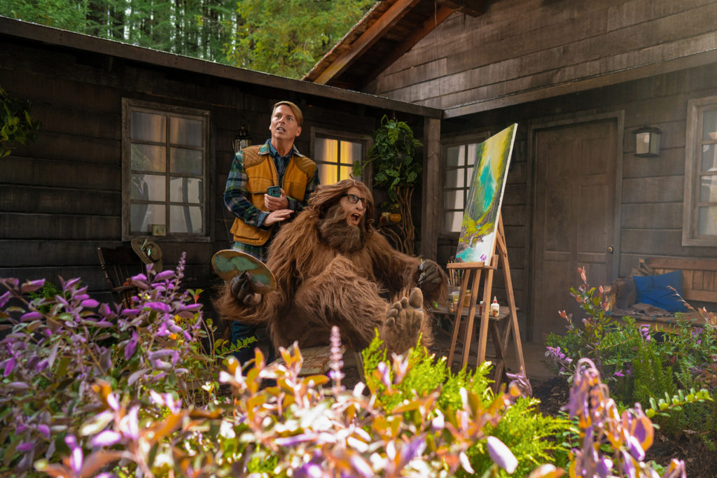 Kenneth Parcell and a "Tina Fey" dressed as Sasquatch enjoy a tranquil getaway to a Wyoming cabin for Booking.com