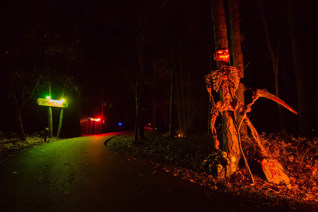 Dark street with a huge illuminated skeleton is part of the scenery on the Woodlock Pines Haunted Hayride. Photo c. Woodloch.com