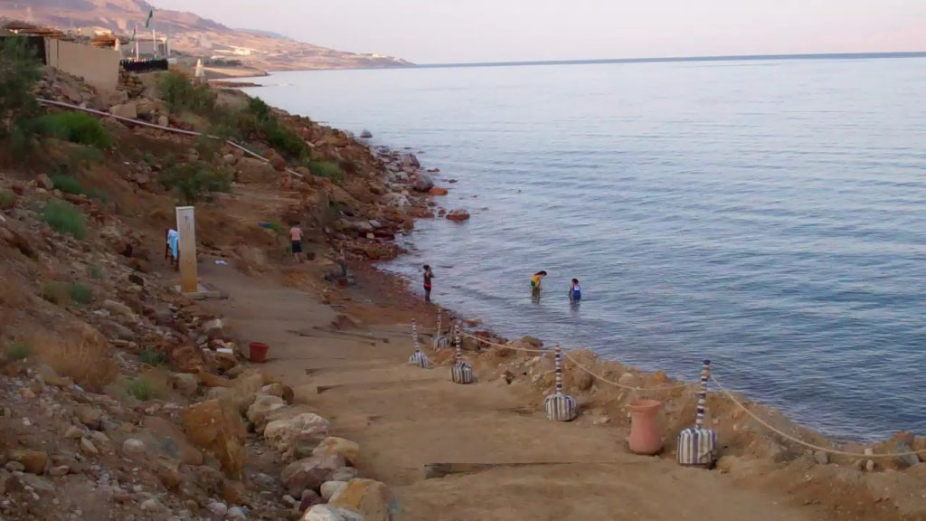 Bathers descend to the shore of the Dead Sea and prepare to float on the very salty water. Photo c. Kyle McCarthy