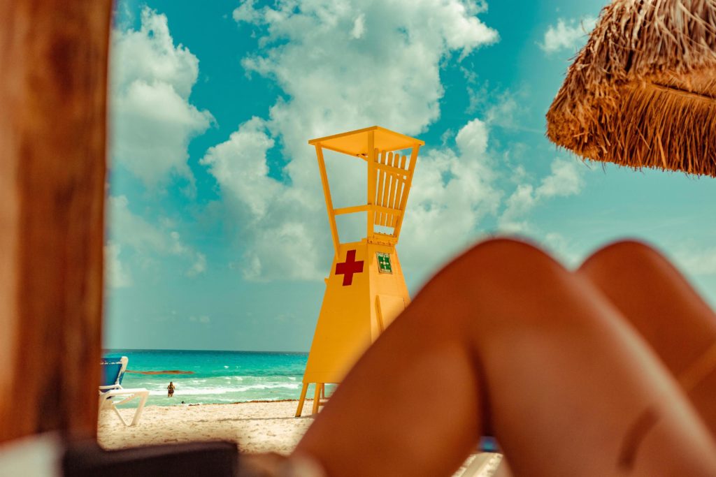 Sunbather under a thatch palapa at the beach in Cancun, Mexico. Photo by Leo Rossatti for pexels.