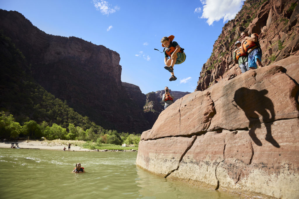 Kids jumping off rocks into the Green River at the Gates of Lodore, Dinosaur National Monument, Utah on an OARS rafting trip. Photo by John Webber for OARS