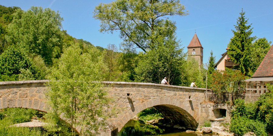 Bike over the River Tauber on a stone bridge as you discover the history of Rothenburg o.d.T. along Germany's Romantic Road. Photo c. Fuchsmuehle.de