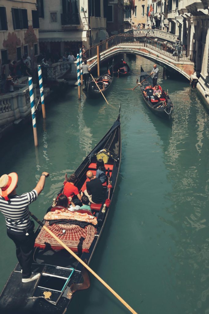 Gondoliers paddle tourists on the canals of Venice. Photo by Efrem Efre for pexels.