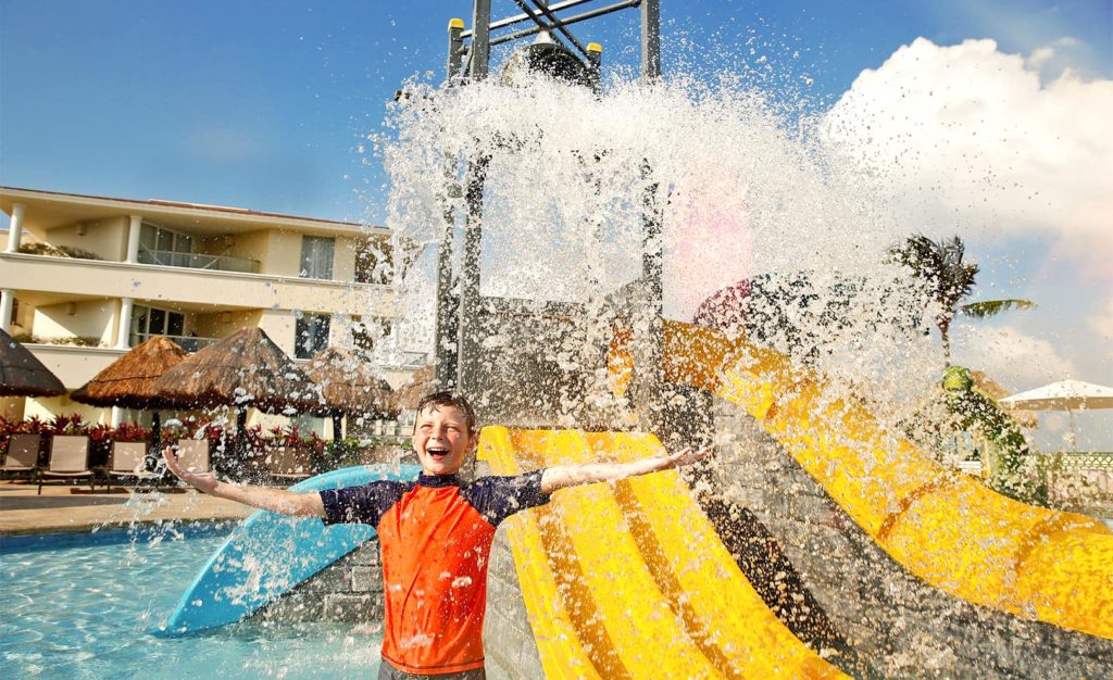 Boy enjoying being splashed with water at the splash zone pool at the Moon Palace Resort. Photo c. Palace Resorts