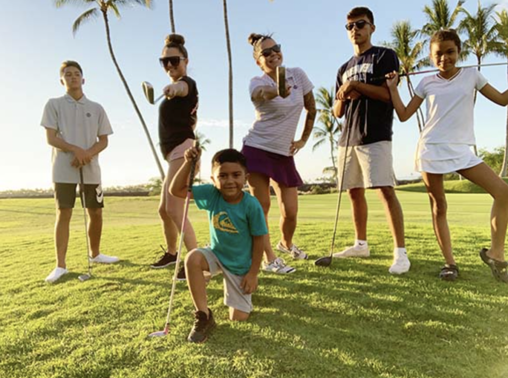 Kid pose with golf clubs at the Hilton Waikoloa Resort in Hawaii.