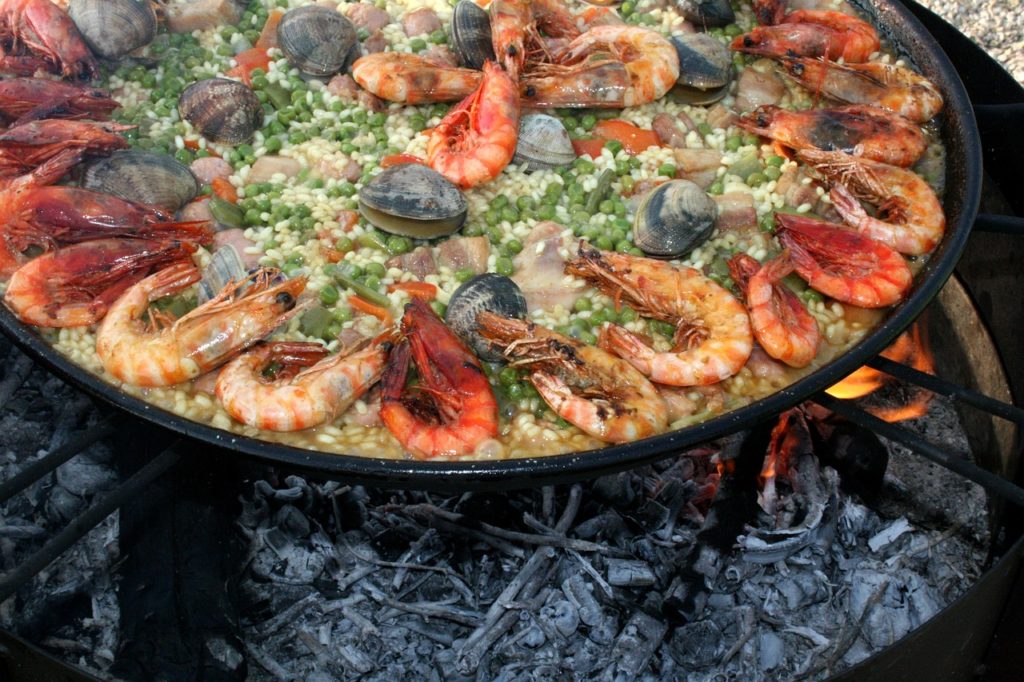 A casserole of Valencian style paella cooking over a grill along the Costa Dorada of Spain. Photo c. Estudio Web Doce for pixabay