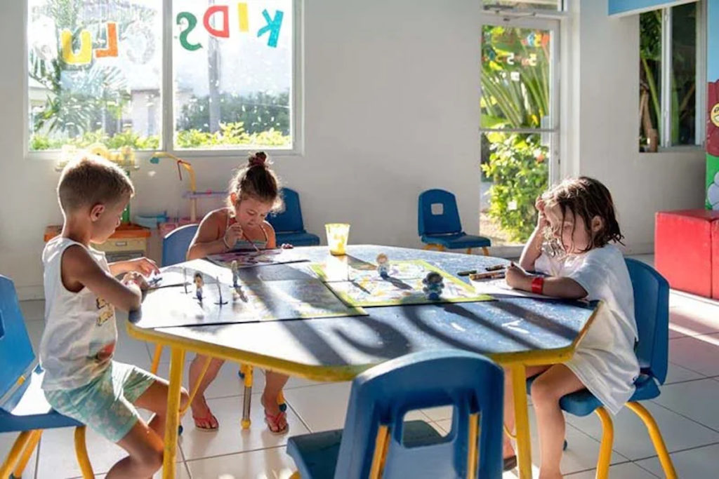 Three children are working on crafts projects at Viva Fortuna Beach kids club in the Bahamas. Photo c. Viva Wyndham