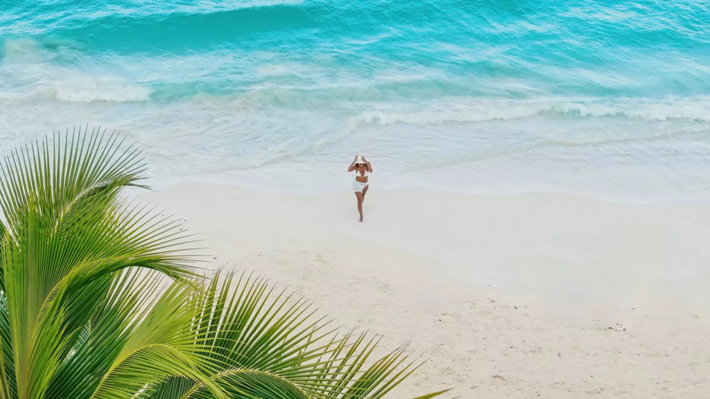Aerial view of woman walking on pristine white sand beach in Miches, Dominican Republic. Photo c. Viva Miches by Wyndham