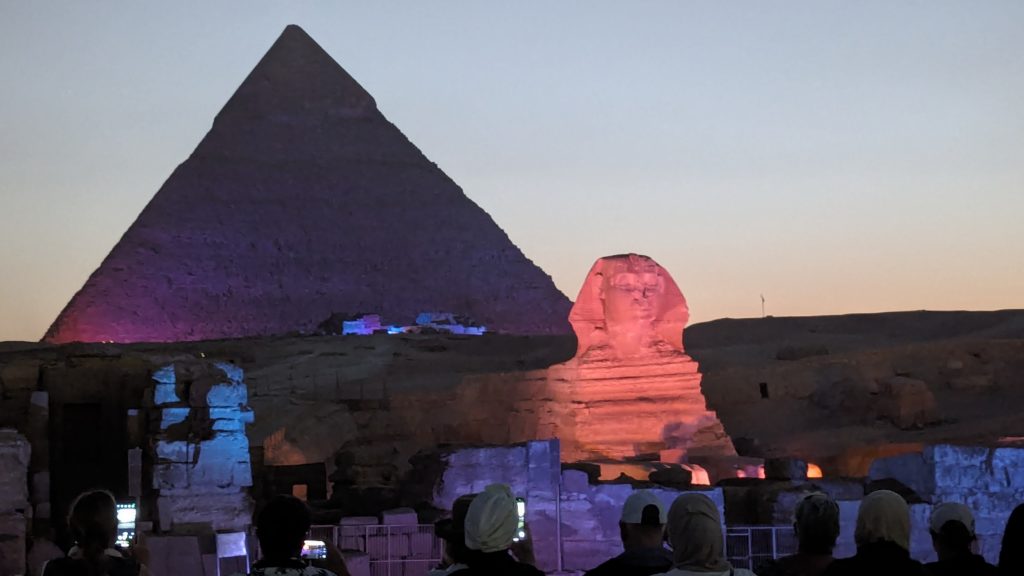 Colorful light projections are cast on The Sphinx and three Pyramids of Giza as a narrator recites the history of Ancient Egypt in the Pyramids Sound & Light Show.