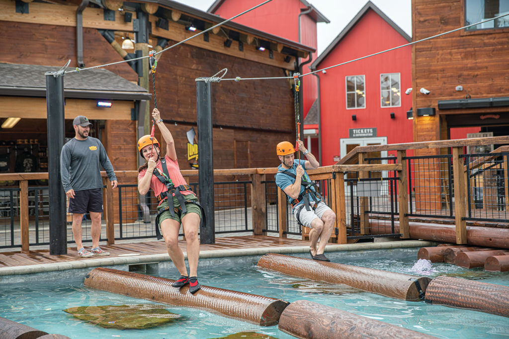 Two people test their balance rolling logs in the adventure park outside Paula Deen's Lumberjack Feud Show in Pigeon Forge.