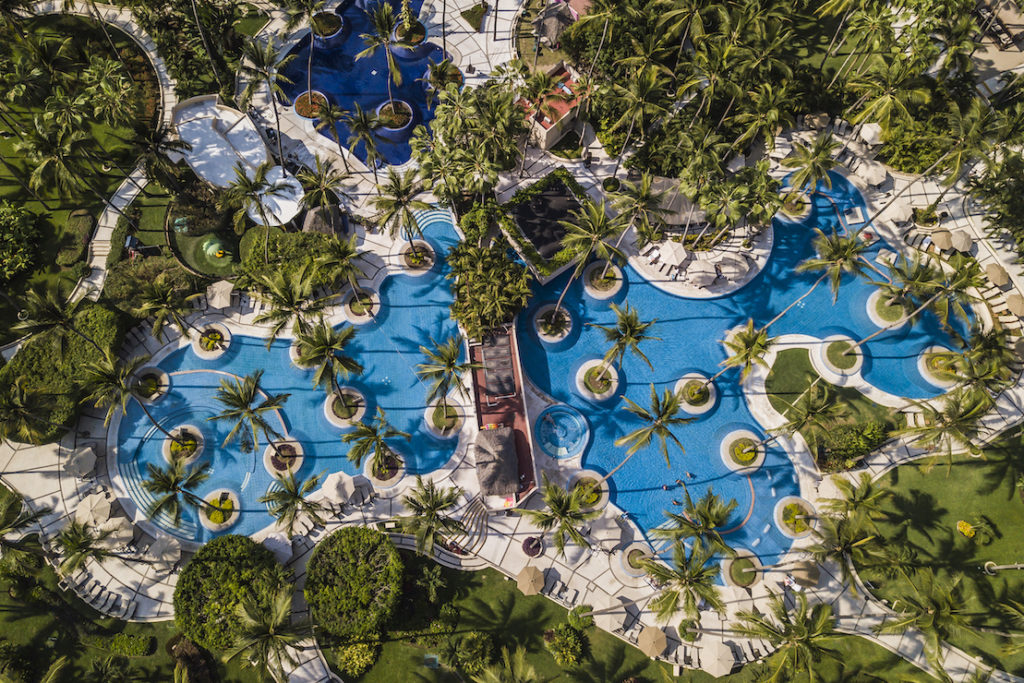 Aerial view of the resort's two swimming pools reveals the palms and small islets that provide shade. Photo c. Westin Resort & Spa, Puerto Vallarta.