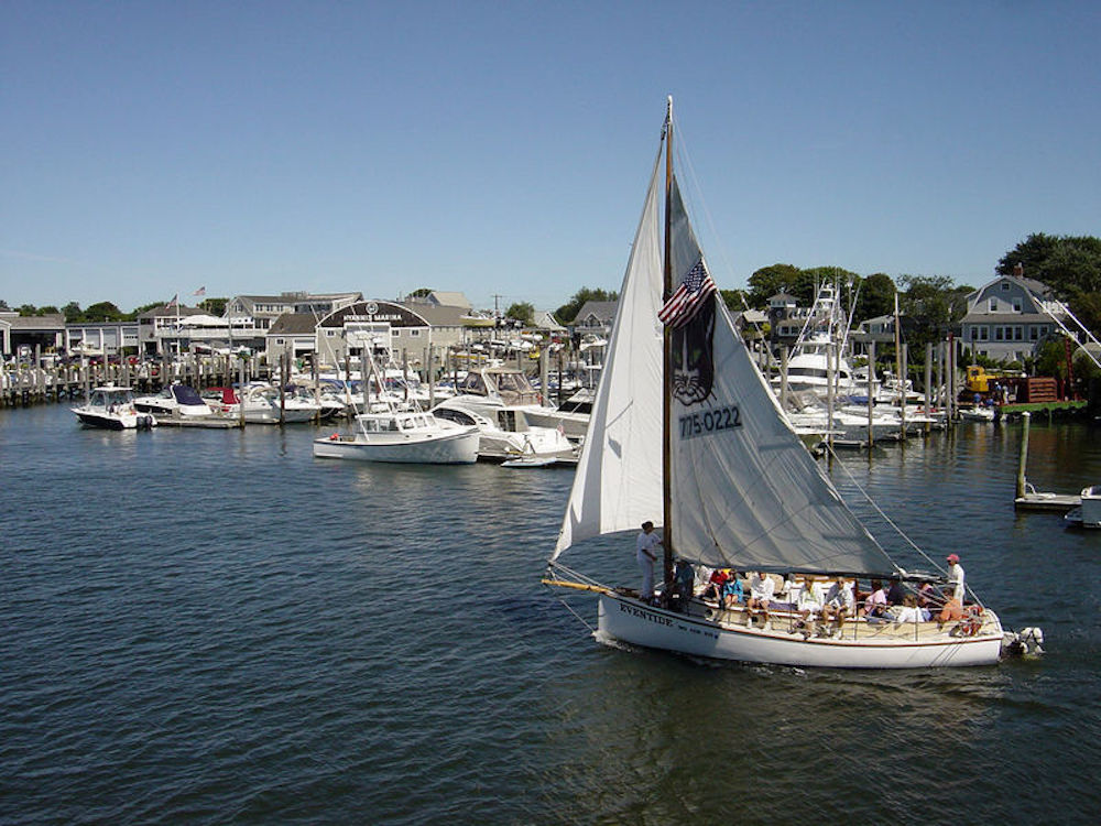 Sailboat leaves Hyannis Port harbor with a group of tourists heading out to the Atlantic for views of the Cape Cod seashore.