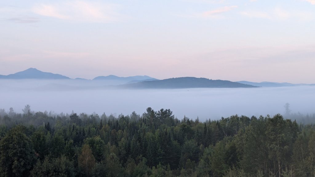 Morning fog rises above the forest at the Mountain View Grand, almost obscuring the view of the Presidential Range.