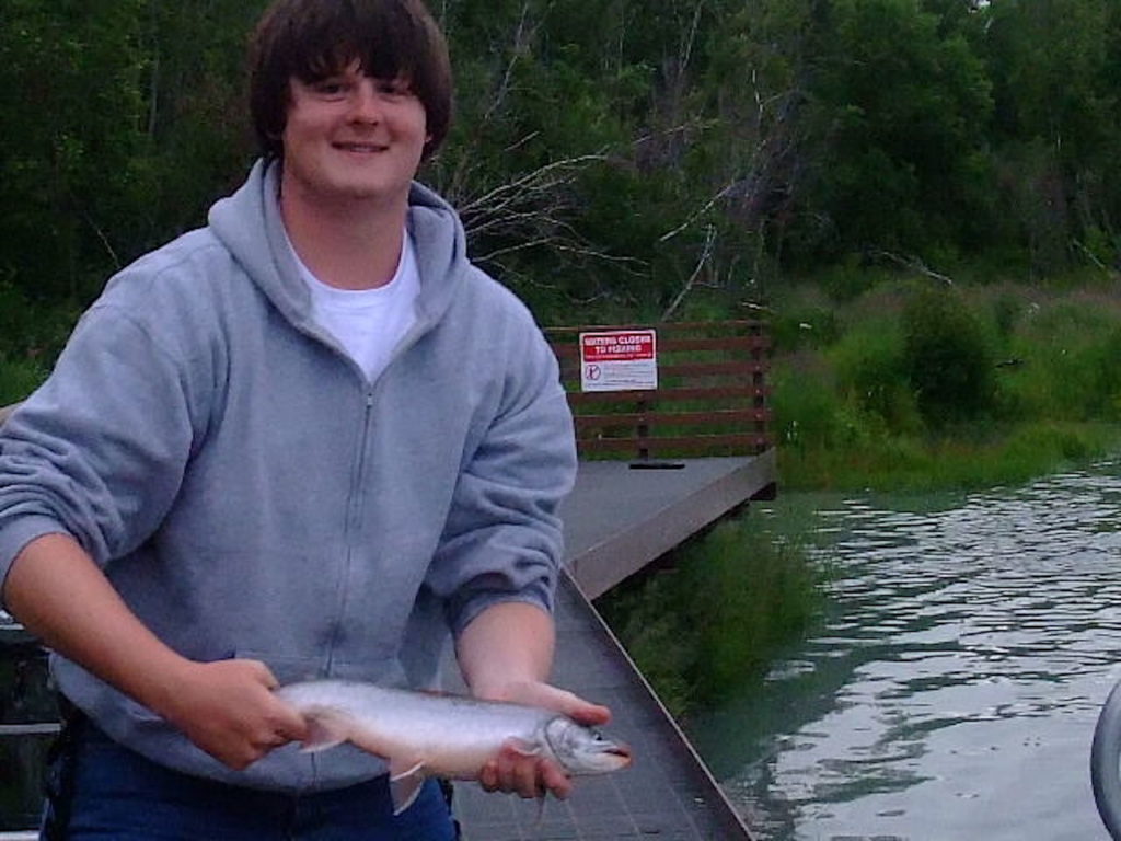 Boy holding his catch while fishing at a mountain stream.