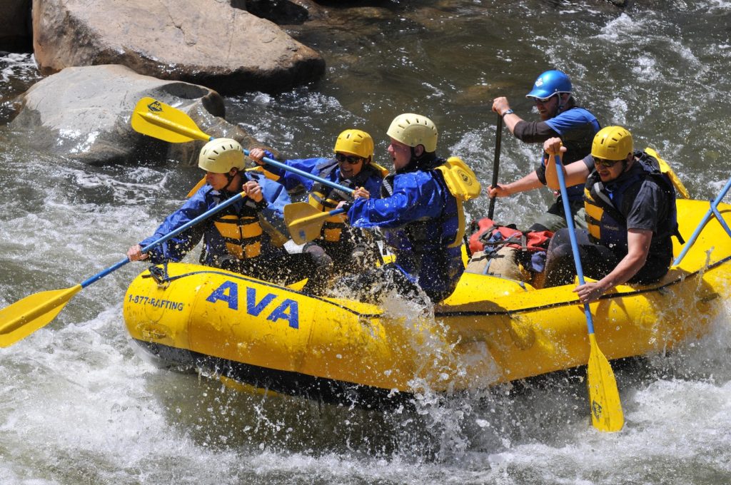 Paddlers guide a whitewater rafting boat on a Utah river in summer.