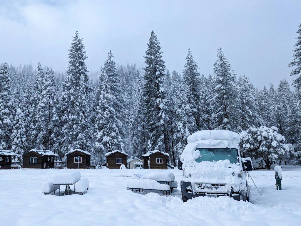 Campervan or RV blanketed in snow in the middle of a quiet winter wonderland. Photo c. dudubangbang for pexels.