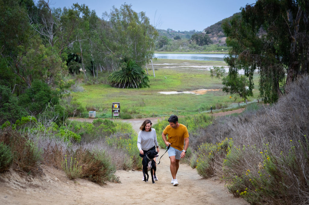 Couple hiking with a dog at Batiguitos Lagoon. Photo c. VisitCarlsbad