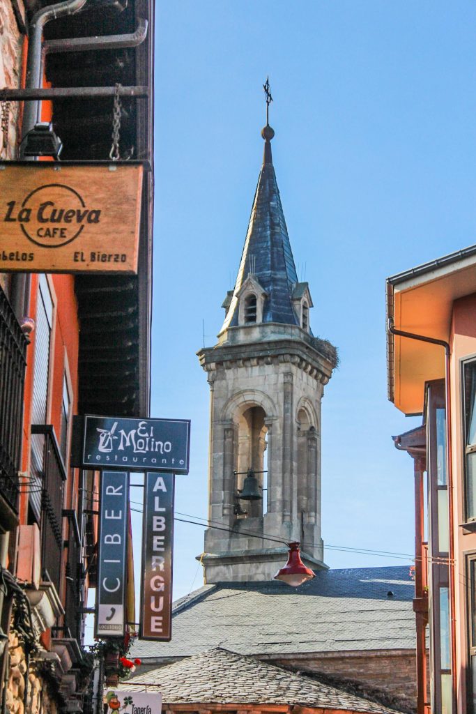 The church steeple and sign for an inn and cafes in the historic town of El Bierzo along the Camino. Photo by Lan Yao for pexels.