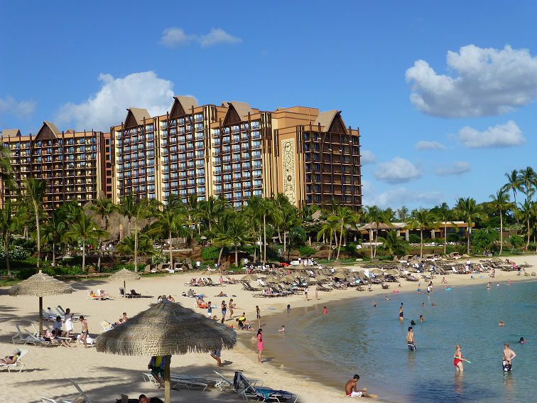 Aulani towers over a pretty beach and resort pool. - disney resort hawaii