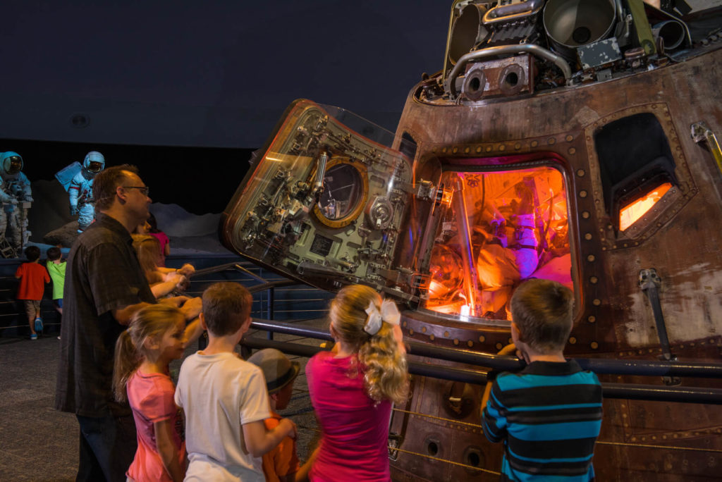 Family studies the interior of a space capsule at Space Center Houston. Photo c. Space Center Houston