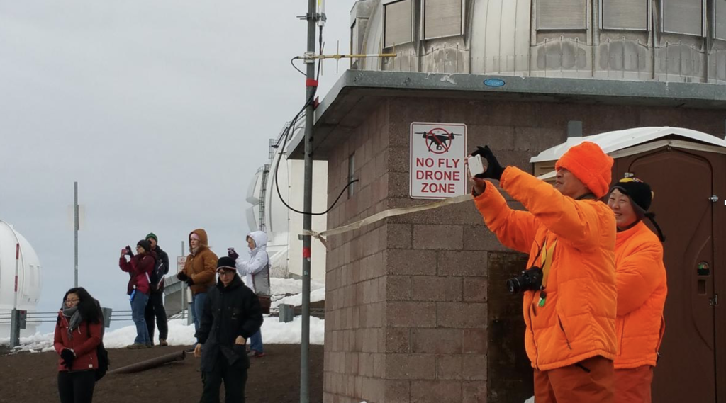 Tourists bundled up against the cold outside the observatories take pictures on top of Maunakea.