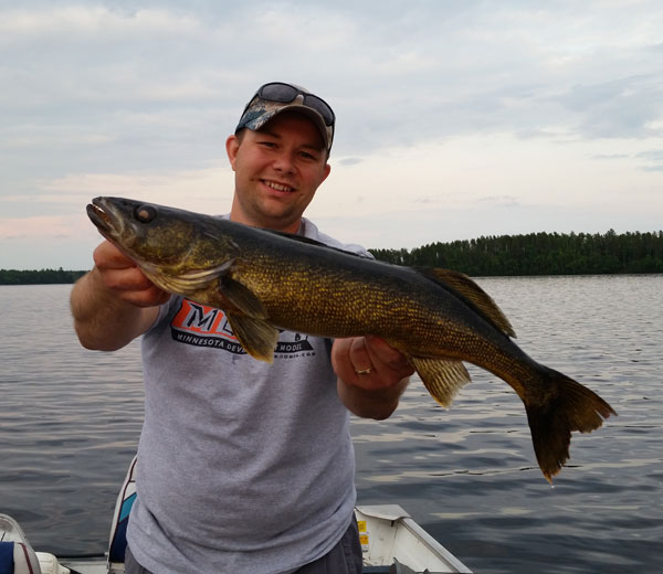 Fisherman at Camp Northern Lights shows off fish he caught.