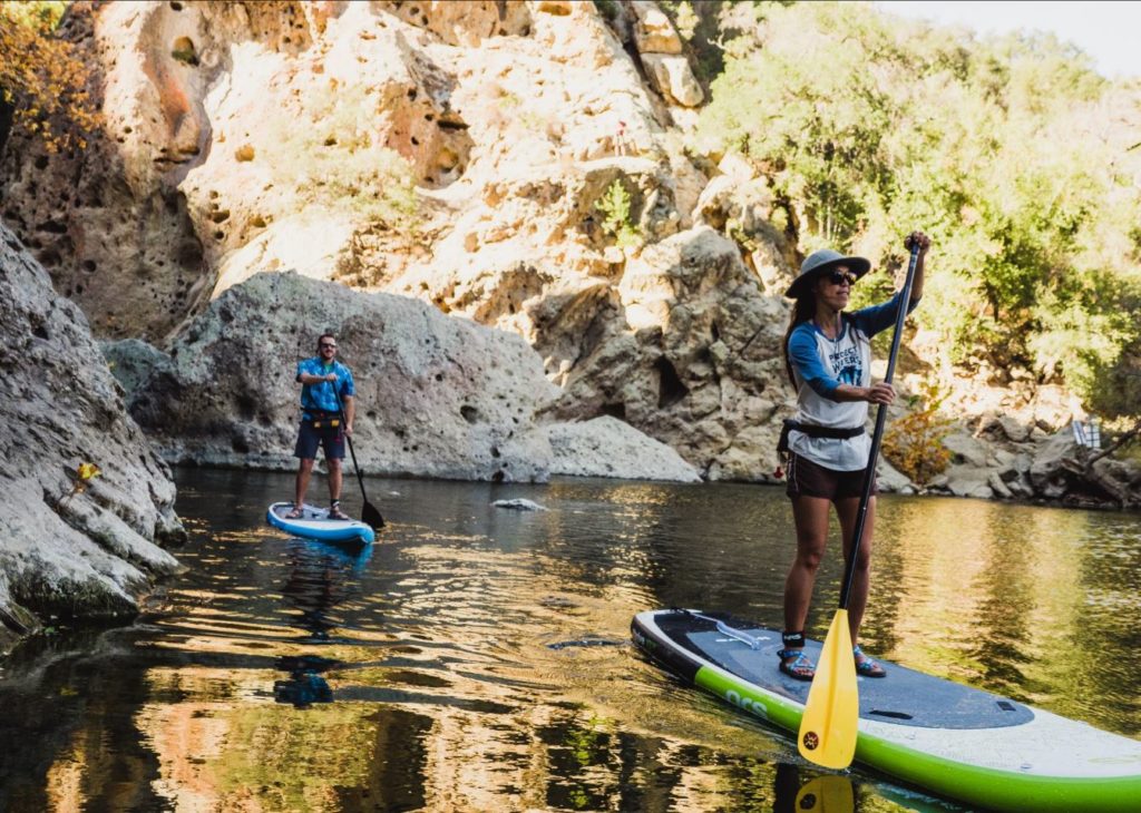 Two standup paddleboarders on a scenic river.