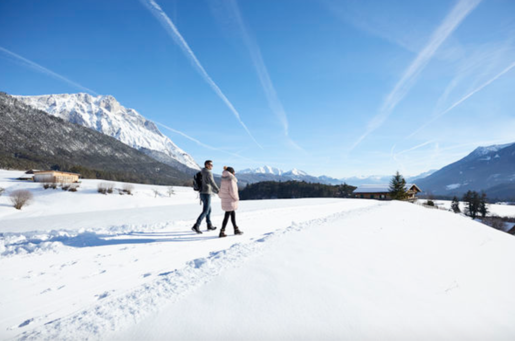 Young couple hiking in the snow outside Innsbruck, Austria with Alps in background.