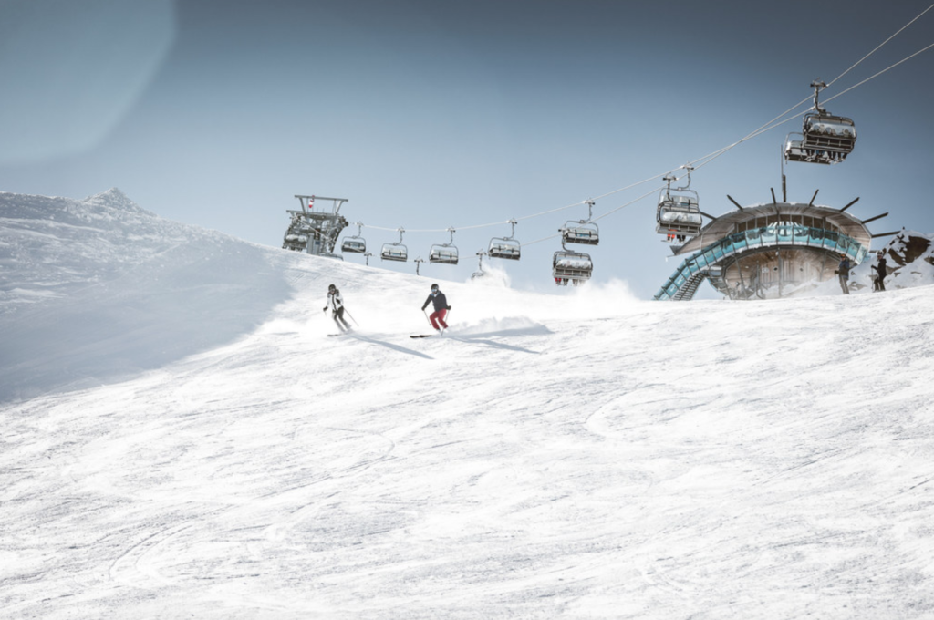 Skiers on slopes of Obergurgl, Austria with modern chairlift in the background.