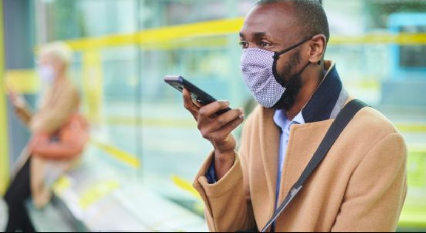 Man wearing mask talks into cellphone.