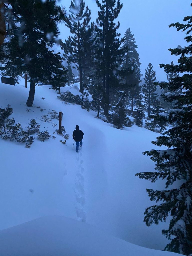 Man hikes through deep snow by himself in the backcountry of Alpine Meadows at Lake Tahoe.