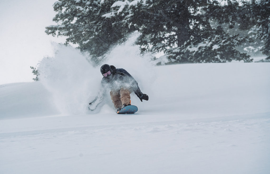 Snowboarder at Snow Basin in deep powder, photo by Brooks Roe for Snowbasin.